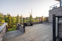 Spacious paver patio with stone veneer perimeter walls and glass panel railing - 