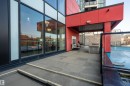 Exterior patio area featuring red architectural accents and dark-framed floor-to-ceiling windows - #610 5151 Windermere Bv Sw, Edmonton, AB  - Outdoor With Balcony With Exterior 