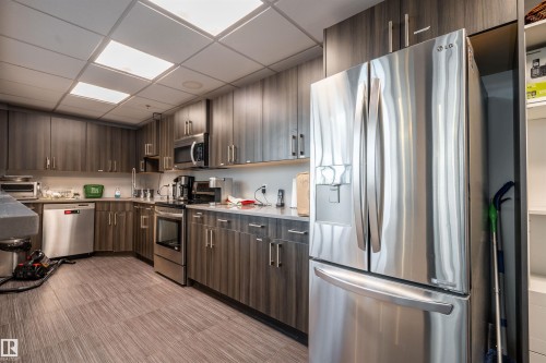 Kitchen featuring wood-finish cabinetry, stainless steel appliances, and wood-finish flooring - #610 5151 Windermere Bv Sw, Edmonton, AB - Indoor Photo Showing Kitchen With Stainless Steel Kitchen