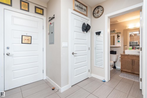 Light gray tile flooring extends through this interior space, featuring a modern bathroom with a wood-finish vanity, vessel sink, and light-toned countertop - #610 5151 Windermere Bv Sw, Edmonton, AB - Indoor Photo Showing Other Room