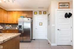 Kitchen featuring wood cabinetry, stainless steel refrigerator, granite-style countertops, and mosaic tile backsplash - 