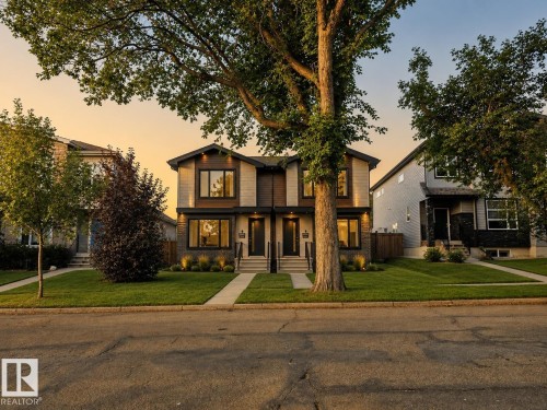 Duplex exterior featuring contemporary architecture, multiple windows, front entryways with exterior lighting, and landscaped grounds with mature trees - 4 Muir Drive, St. Albert, AB 