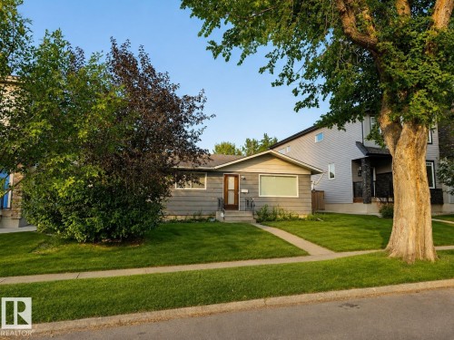 Gray siding exterior with a brown entry door, white trim windows, and a concrete pathway - 4 Muir Drive, St. Albert, AB 
