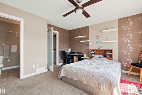 Ceiling fan with integrated lighting, wood-finish flooring, accent wall with decorative wall covering, built-in shelving, and frosted glass interior door - 10833 63 Avenue Nw, Edmonton, AB 