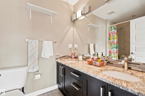Dual vanity with undermount sinks, speckled countertop, and dark wood-finish cabinetry - 10833 63 Avenue Nw, Edmonton, AB 
