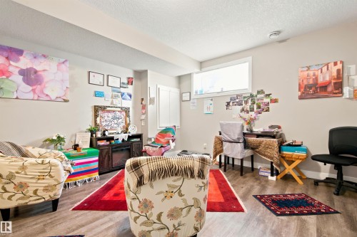 Wood-finish flooring with neutral wall tones and a built-in electric fireplace - 10833 63 Avenue Nw, Edmonton, AB 
