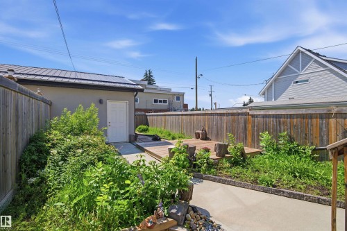 Rear yard featuring a concrete pathway, a wooden fence, and a raised wooden deck - 10833 63 Avenue Nw, Edmonton, AB 
