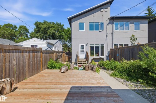 Spacious wooden deck with a privacy fence, concrete walkway, and an exterior door providing access to the residence - 10833 63 Avenue Nw, Edmonton, AB 