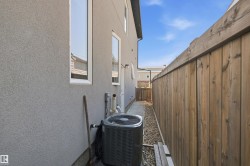Stucco exterior wall with multiple windows, air conditioning unit, gravel landscaping, and wood privacy fencing - 