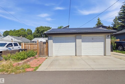 Two-car garage with white panel doors, concrete driveway, and a black metal roof - 10833 63 Avenue Nw, Edmonton, AB 