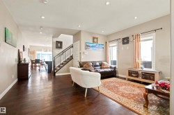Expansive living area featuring rich wood-finish flooring, recessed lighting, and large windows - 