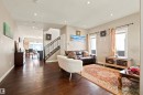 Expansive living area featuring rich wood-finish flooring, recessed lighting, and large windows - 10833 63 Avenue Nw, Edmonton, AB 