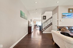 Dark wood-finish flooring throughout, recessed lighting, and a staircase with a dark wood handrail and metal spindles - 