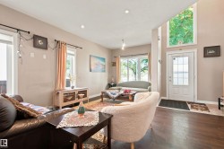 Rich wood-finish flooring, recessed lighting, and a white paneled door with decorative glass - 