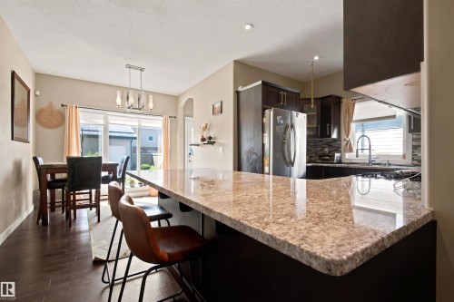 Kitchen featuring granite countertops, dark wood-finish cabinetry, stainless steel appliances, and a tile backsplash - 10833 63 Avenue Nw, Edmonton, AB 