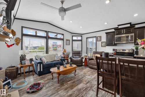 Open-concept living area with wood-finish flooring, a contemporary ceiling fan, and recessed lighting - 4204 47 Street, Wetaskiwin, AB - Indoor