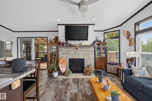 Living area featuring a stone-clad fireplace and wood-finish flooring - 4204 47 Street, Wetaskiwin, AB - Indoor Photo Showing Living Room With Fireplace