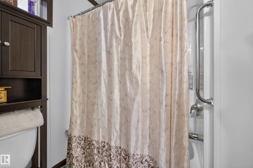 Shower enclosure featuring a chrome grab bar and integrated shelving - 4204 47 Street, Wetaskiwin, AB - Indoor Photo Showing Bathroom