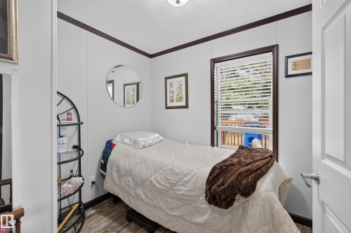 Interior room featuring vertical paneling, dark trim, and wood-finish flooring - 4204 47 Street, Wetaskiwin, AB - Indoor Photo Showing Bedroom