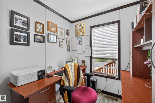 Functional office space featuring wood-finish desk with drawer storage, dark wood-finish trim, and a window with horizontal blinds - 4204 47 Street, Wetaskiwin, AB - Indoor Photo Showing Other Room