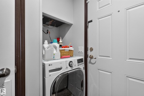 Dedicated laundry area featuring a front-load washer and upper shelving - 4204 47 Street, Wetaskiwin, AB - Indoor Photo Showing Laundry Room