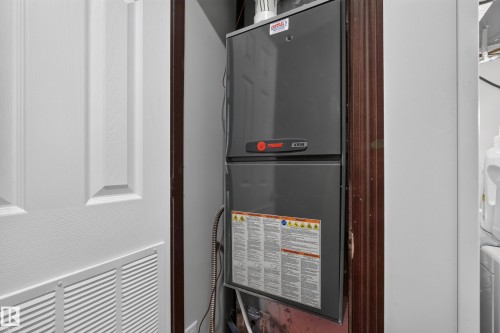 Utility closet with a panel door featuring a lower vent, housing a gray furnace unit - 4204 47 Street, Wetaskiwin, AB - Indoor Photo Showing Basement