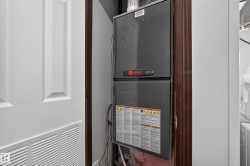 Utility closet with a panel door featuring a lower vent, housing a gray furnace unit - 