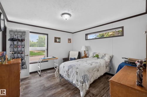 Bright room featuring wood-finish flooring, white panel walls, and dark trim - 4204 47 Street, Wetaskiwin, AB - Indoor Photo Showing Bedroom