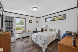Bright room featuring wood-finish flooring, white panel walls, and dark trim - 