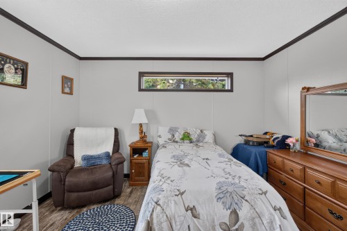 Interior room featuring light gray wall paneling, dark wood-finish trim, and wood-finish flooring - 4204 47 Street, Wetaskiwin, AB - Indoor Photo Showing Bedroom