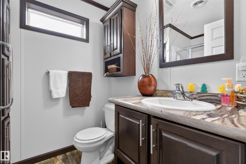 Bathroom vanity with dark wood-finish cabinetry, a white basin, and a patterned countertop - 4204 47 Street, Wetaskiwin, AB - Indoor Photo Showing Bathroom