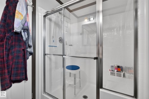 Shower enclosure with sliding glass doors, chrome hardware, and white tile-look surround - 4204 47 Street, Wetaskiwin, AB - Indoor Photo Showing Bathroom