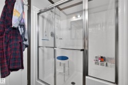 Shower enclosure with sliding glass doors, chrome hardware, and white tile-look surround - 