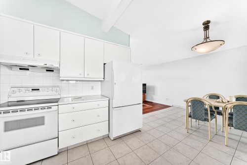 White kitchen cabinetry with tile backsplash, built-in electric range, and integrated refrigerator - 3311 104 Avenue Nw, Edmonton, AB 