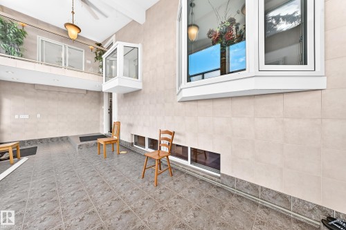 Expansive tiled flooring, a second-story interior balcony with white railings, and a large bay window - 3311 104 Avenue Nw, Edmonton, AB 