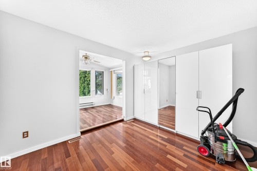 Wood-finish flooring, white walls, built-in white cabinetry, and mirrored closet doors - 3311 104 Avenue Nw, Edmonton, AB 