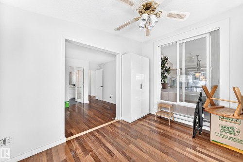Hardwood flooring throughout, a ceiling fan with integrated lighting, a sliding glass door, and a built-in storage cabinet - 3311 104 Avenue Nw, Edmonton, AB 