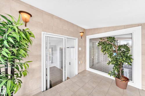 Tile flooring and walls, wall-mounted sconce lighting, and a large fixed window - 3311 104 Avenue Nw, Edmonton, AB 