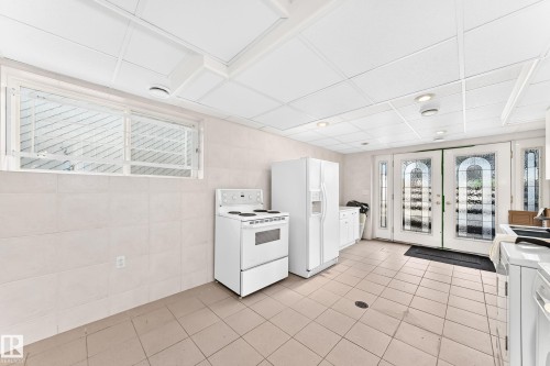 Neutral-toned tiled flooring, white tiled walls, and a dropped ceiling with recessed lighting - 3311 104 Avenue Nw, Edmonton, AB 