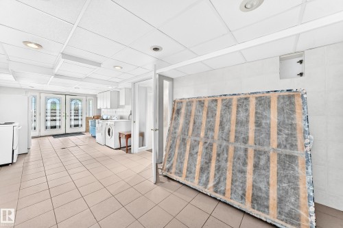 Tile flooring, drop ceiling with recessed lighting, white cabinetry, French doors with arched transoms, and a utility sink - 3311 104 Avenue Nw, Edmonton, AB 