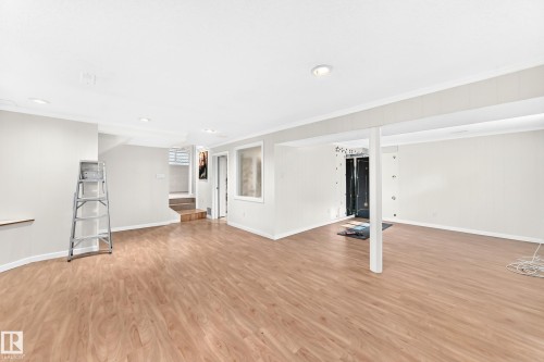 Spacious lower level featuring wood-finish flooring, recessed lighting, white walls, and a staircase - 3311 104 Avenue Nw, Edmonton, AB 