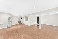 Spacious lower level featuring wood-finish flooring, recessed lighting, white walls, and a staircase - 