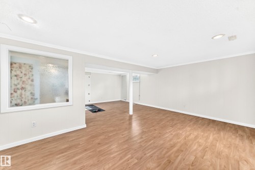 Open-concept interior featuring wood-finish flooring, recessed lighting, and a frosted glass interior window - 3311 104 Avenue Nw, Edmonton, AB 