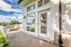 Modern farmhouse exterior featuring clean white vertical siding, expansive glass doors and windows with white framing, and a gravel patio area - 