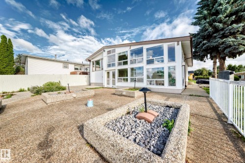 White exterior with extensive fenestration, large concrete patio, and built-in stone planters - 3311 104 Avenue Nw, Edmonton, AB 