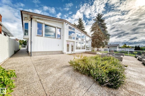 White exterior with multiple windows, glass-paneled double doors, and a decorative concrete patio - 3311 104 Avenue Nw, Edmonton, AB 