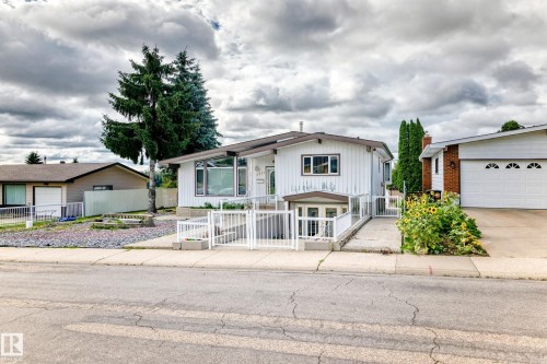 Ranch-style residence featuring white vertical siding, prominent front windows, and a dedicated entrance with white railing - 3311 104 Avenue Nw, Edmonton, AB 