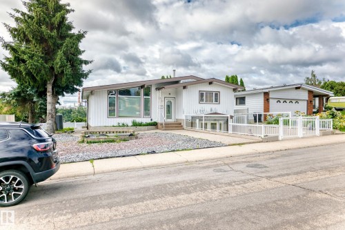 White siding exterior with a dark trim roofline, large picture windows, and a white picket fence - 3311 104 Avenue Nw, Edmonton, AB 