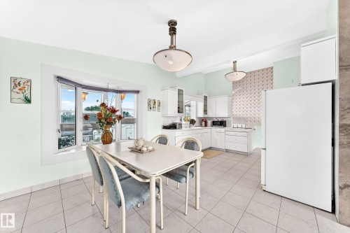 White cabinetry, tiled flooring, bay window, ceiling-mounted light fixtures, and a white refrigerator - 3311 104 Avenue Nw, Edmonton, AB 