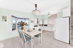 White cabinetry, tiled flooring, bay window, ceiling-mounted light fixtures, and a white refrigerator - 